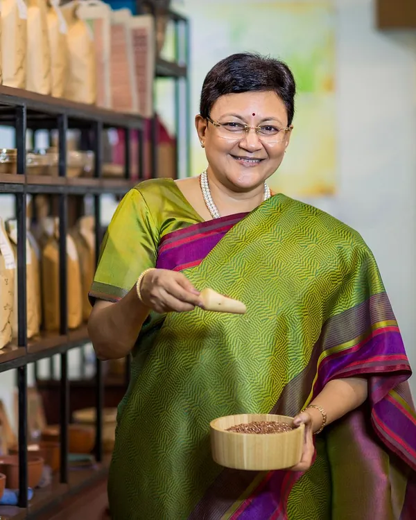 A smiling shop owner holding a spice scoop in her store